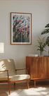 una acogedora sala de estar con un mueble de madera, un sillón beige, un cuadro enmarcado de flores rosas y una maceta.