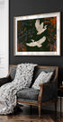 un sofá blanco y negro con una manta blanca y dos almohadas blancas, colocado contra una pared oscura con una pintura enmarcada de dos pájaros blancos volando sobre ella.