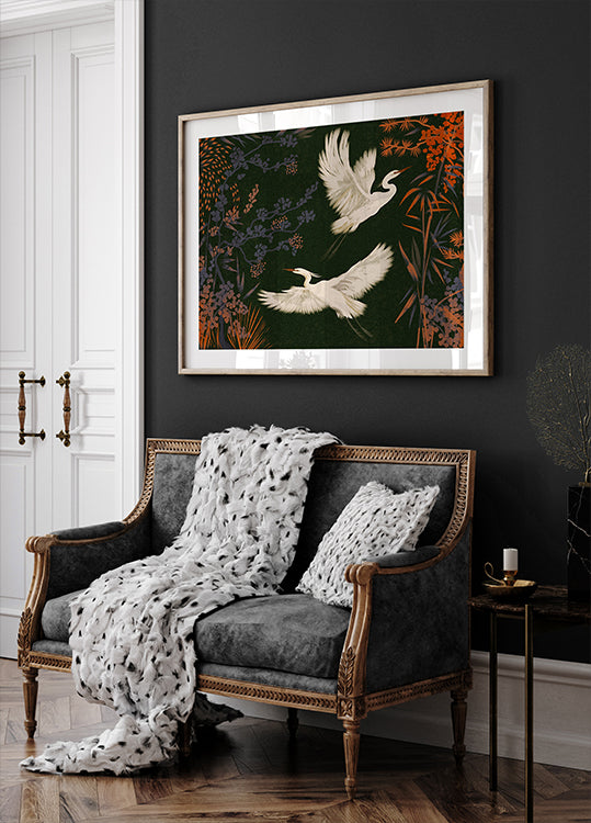 un sofá blanco y negro con una manta blanca y dos almohadas blancas, colocado contra una pared oscura con una pintura enmarcada de dos pájaros blancos volando sobre ella.