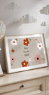 Una impresión enmarcada con un diseño floral y el texto "Baby You are Magic" se muestra en una cómoda de madera, con una linterna de papel decorativa colgando encima.