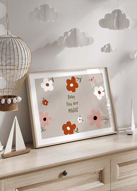 Una impresión enmarcada con un diseño floral y el texto "Baby You are Magic" se muestra en una cómoda de madera, con una linterna de papel decorativa colgando encima.